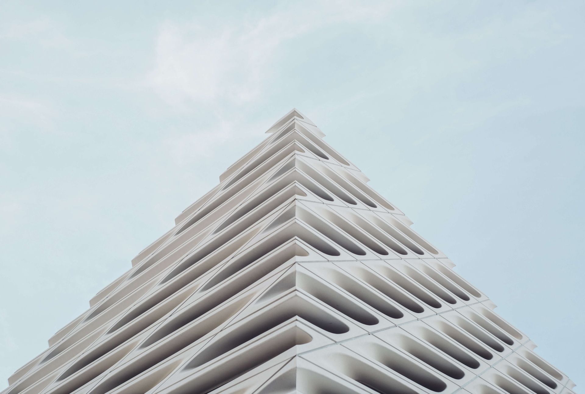 Looking up at a tall white building with a blue sky in the background.