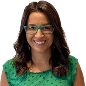 A woman wearing glasses and a green shirt is smiling.