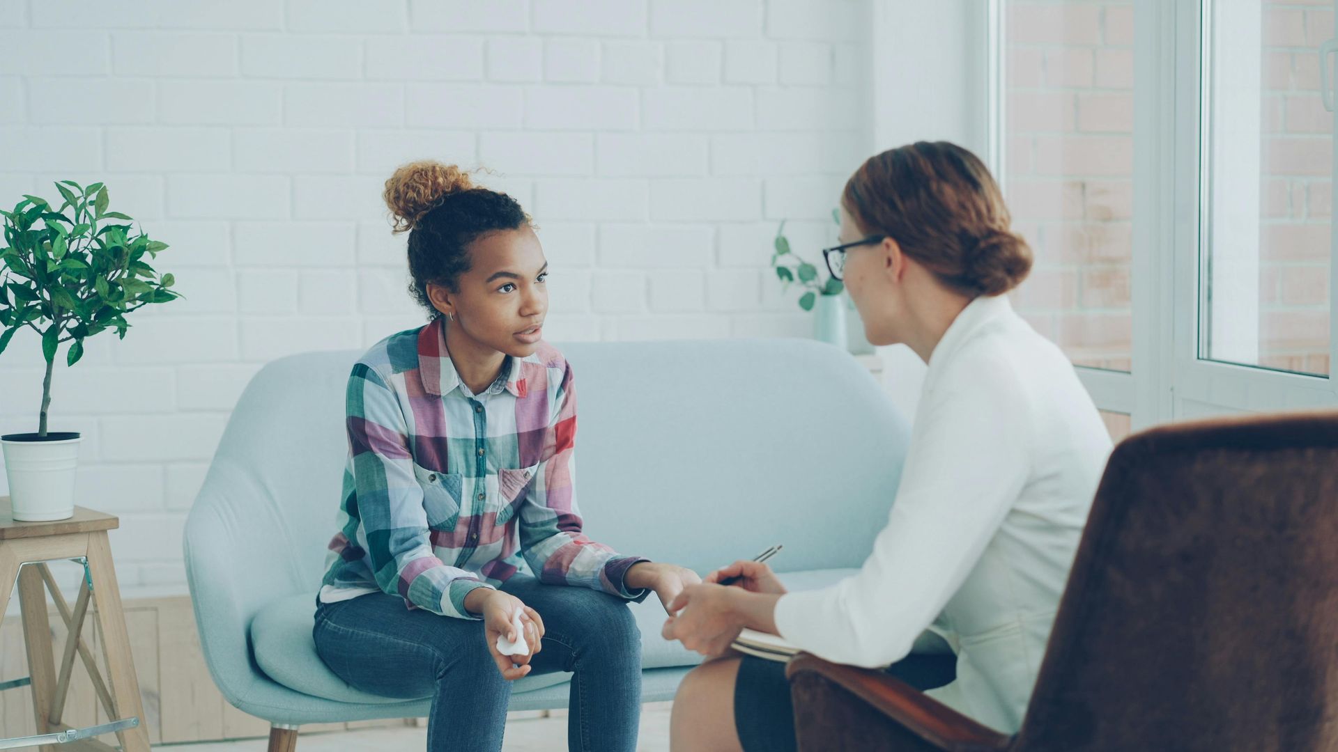 A woman sits on a softa, mid-conversation with a therapist.