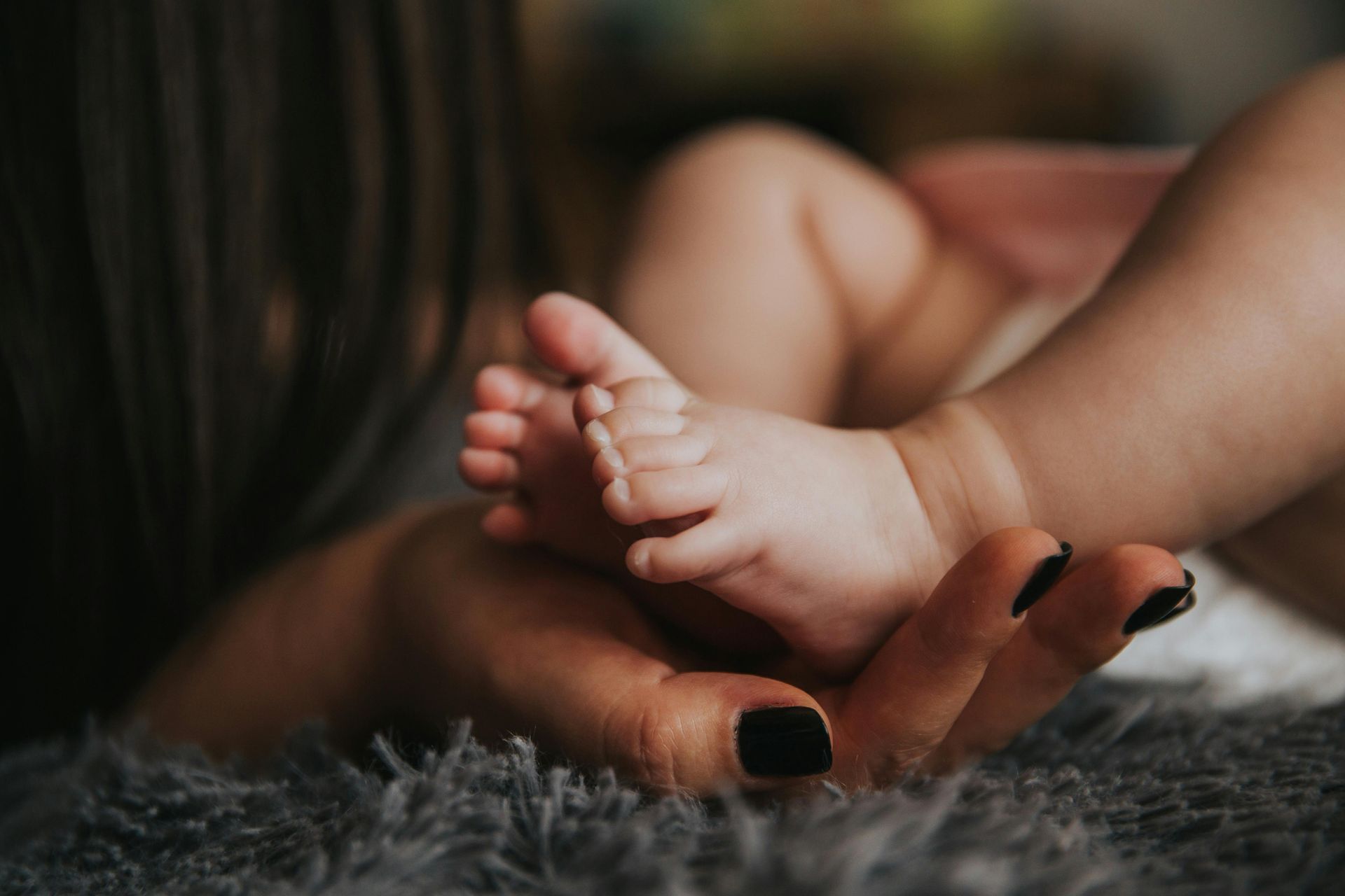 A baby's feet are cradled in the hands of a parent. 