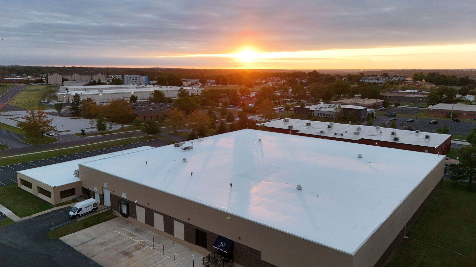 Warehouse roof at sunset with buildings and a town in the background.