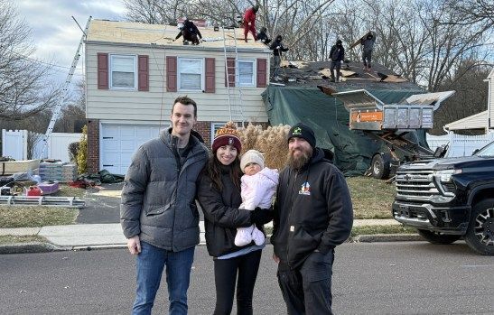 Family pose for a picture with Dan Kingkiner of Essential Exteriors as they install new roof
