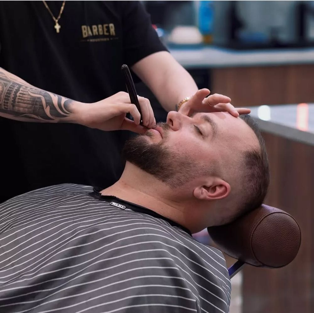 A man is getting his beard shaved by a barber