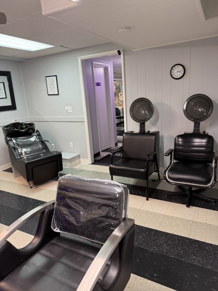 A hair salon with a sink and chairs and a clock on the wall.