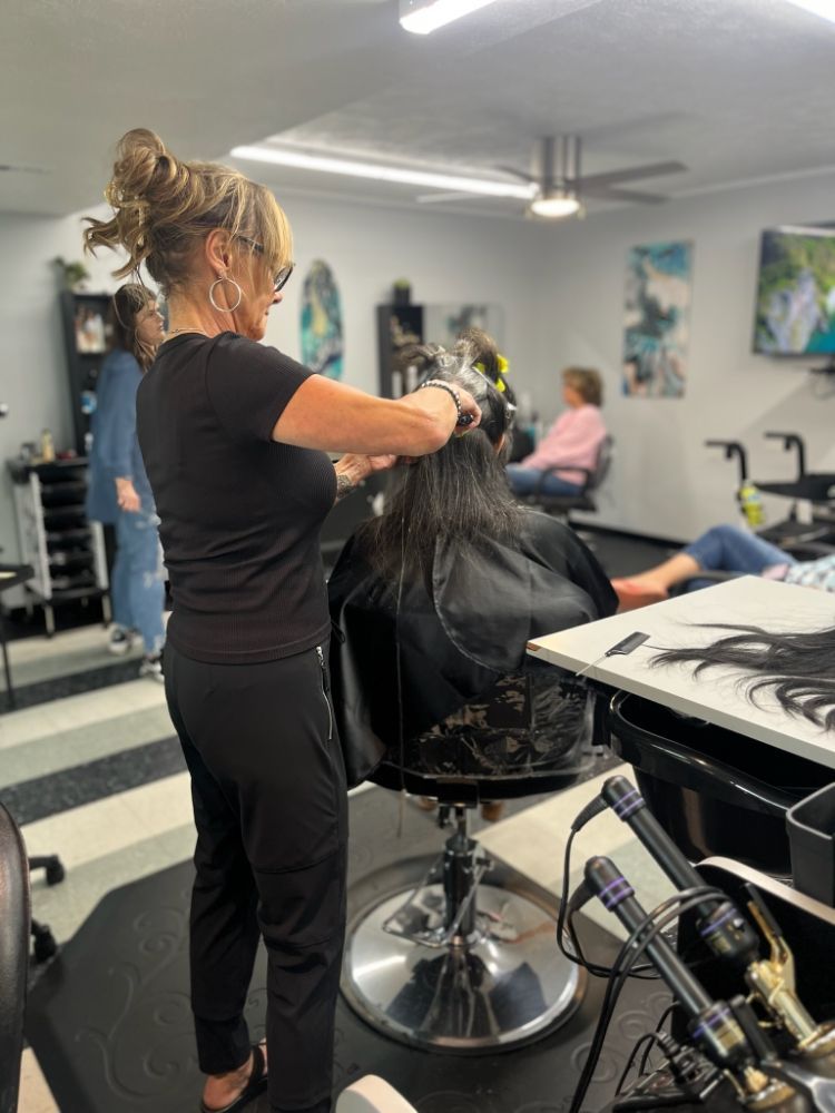 A woman is cutting a woman 's hair in a salon.