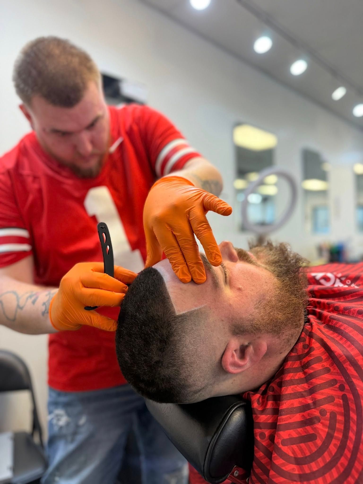 A man is getting his beard shaved by a barber in a barber shop.