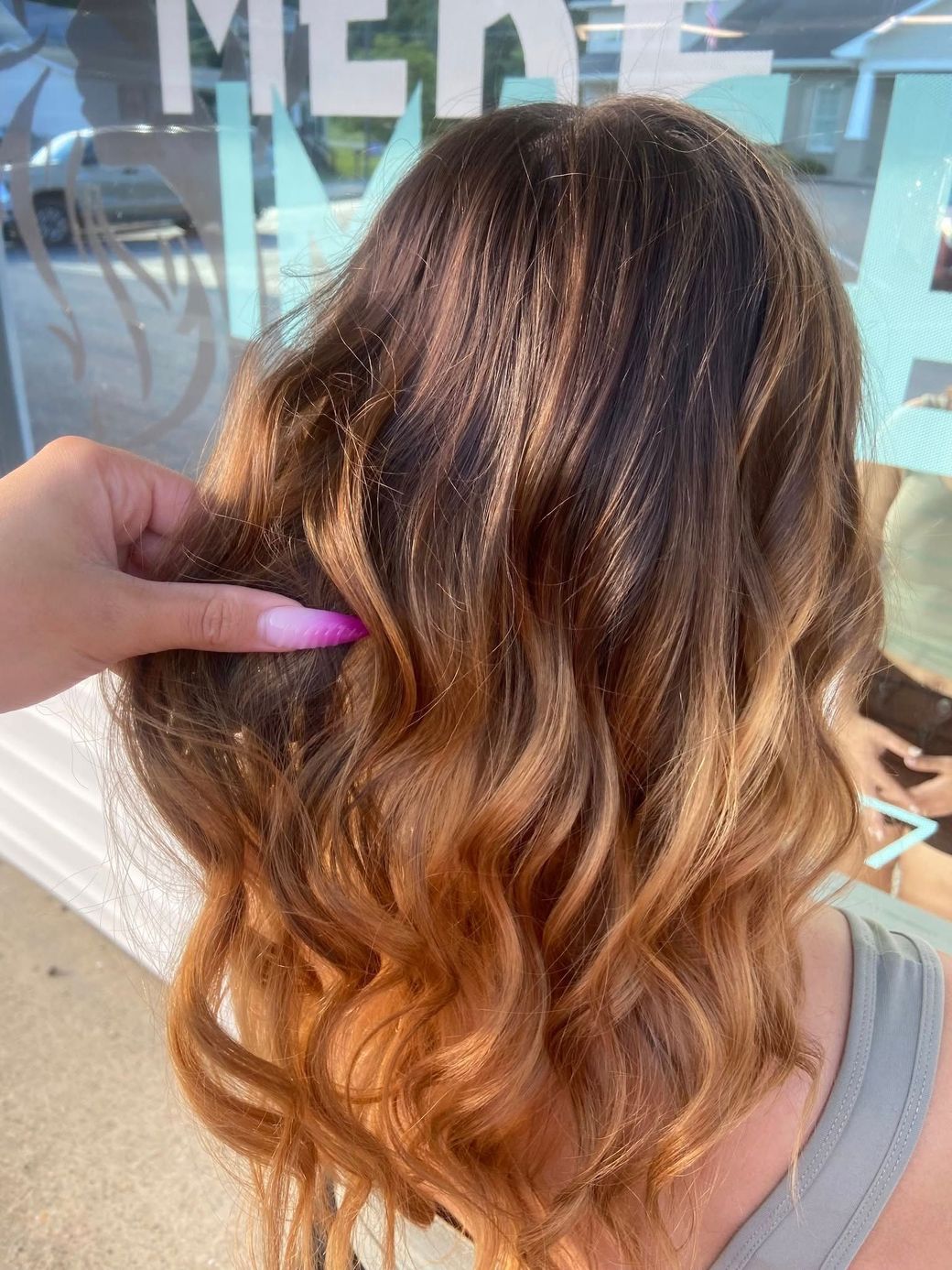 A close up of a woman 's hair with a pink nail.