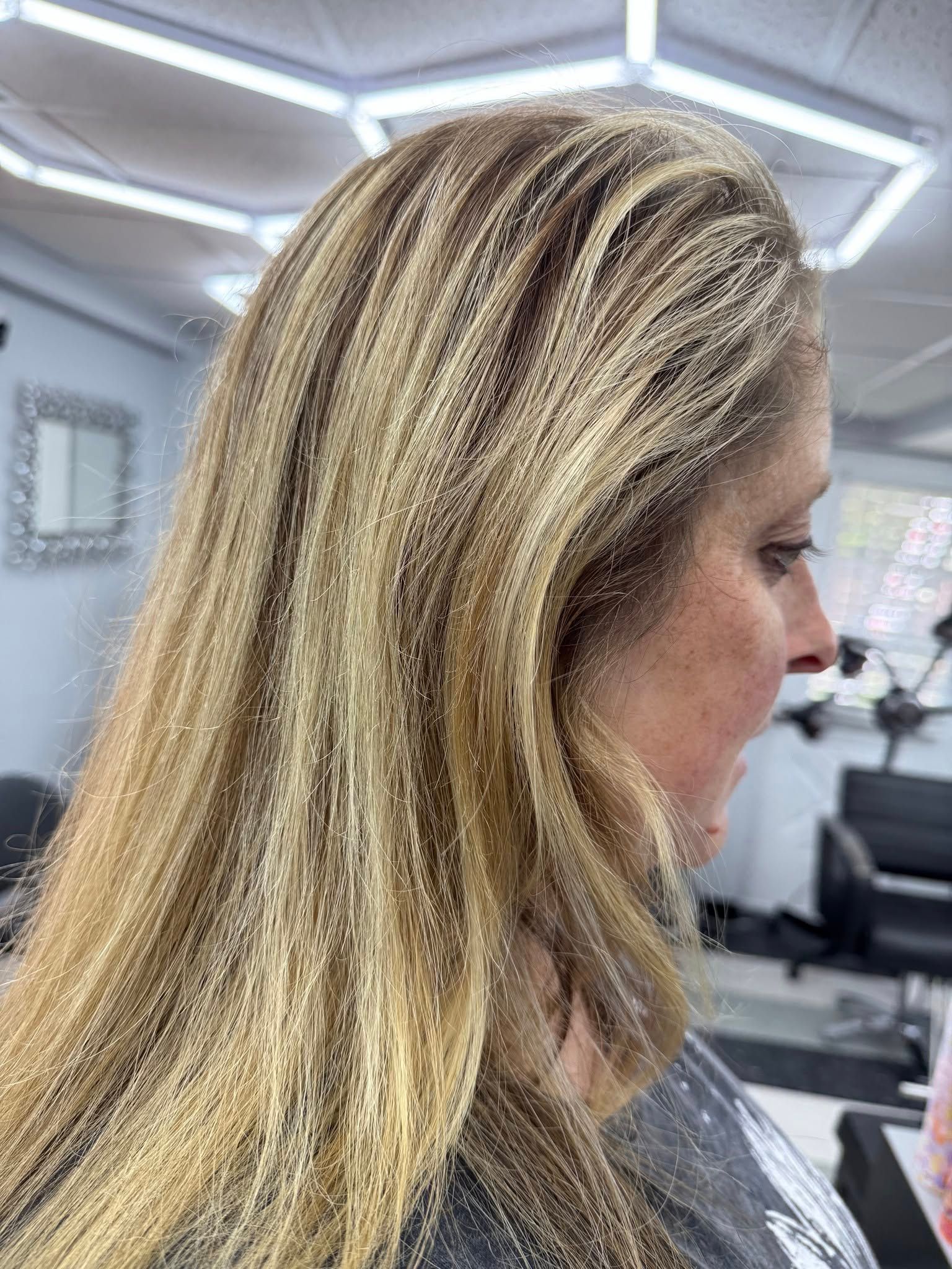 A woman with long blonde hair is sitting in a salon.