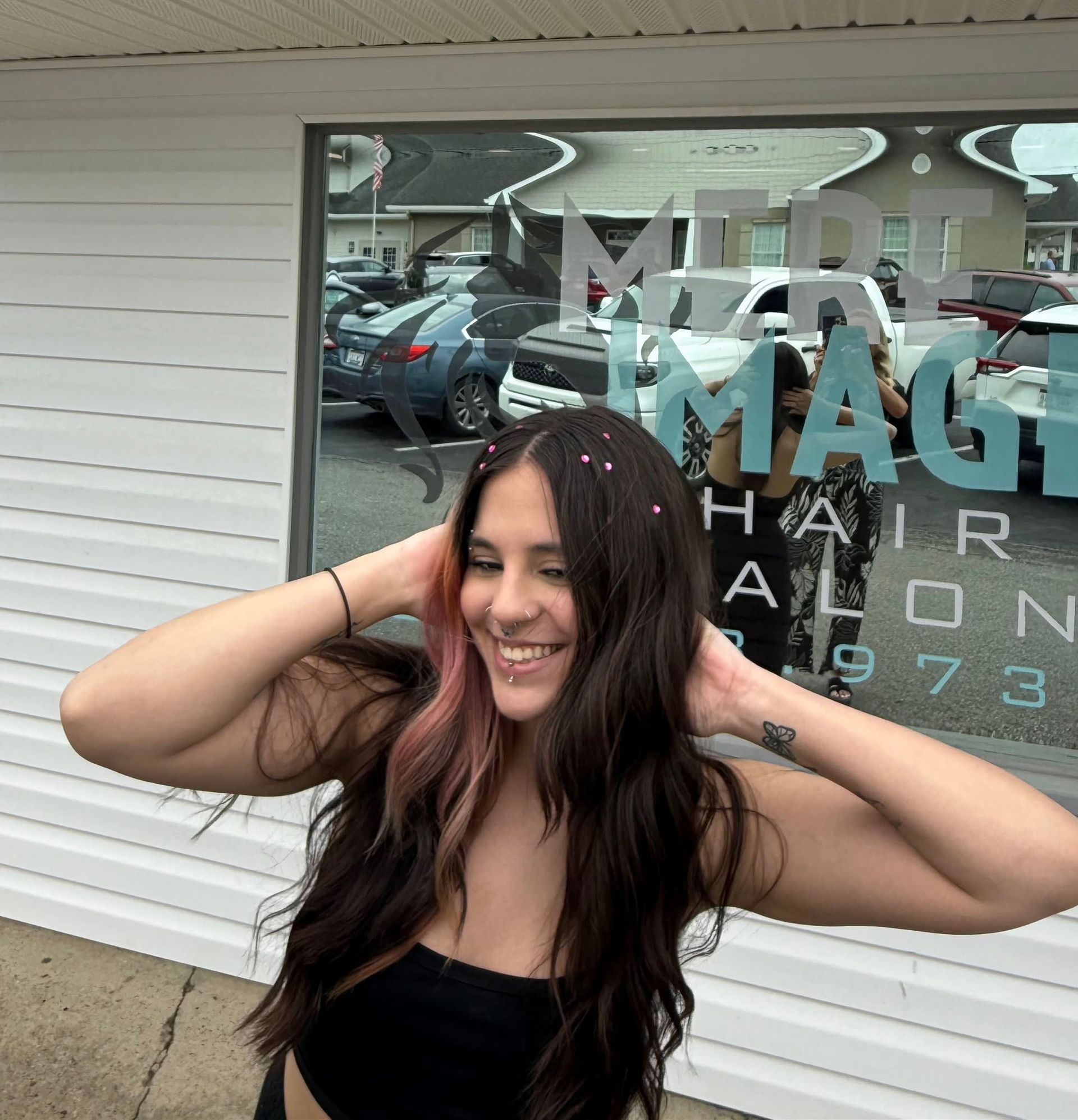 A woman stands in front of a window that says magic hair salon 1973