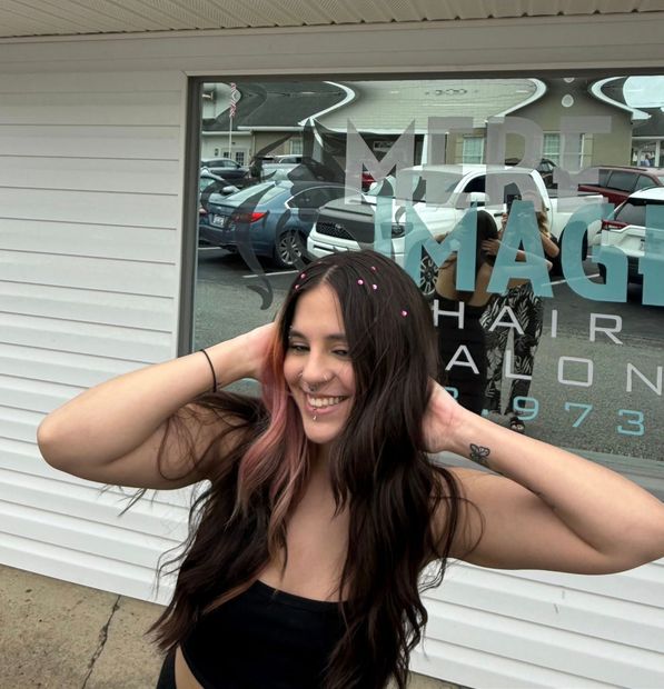 A woman stands in front of a window that says magic hair salon 1973