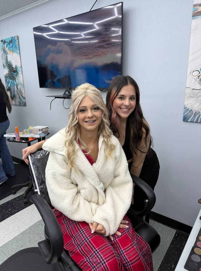 A woman is sitting in a chair next to another woman in a room.