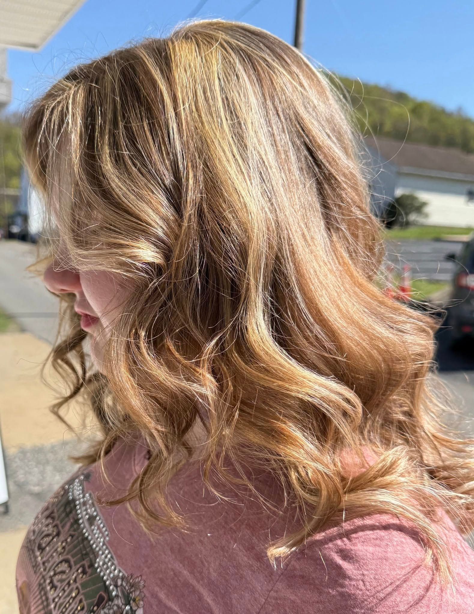 A woman with long blonde hair is standing on a sidewalk.