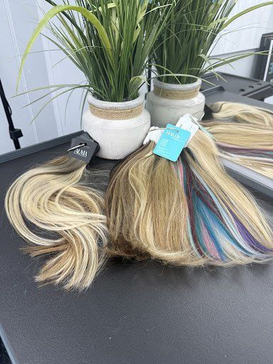 A bunch of hair extensions are sitting on a table next to potted plants.