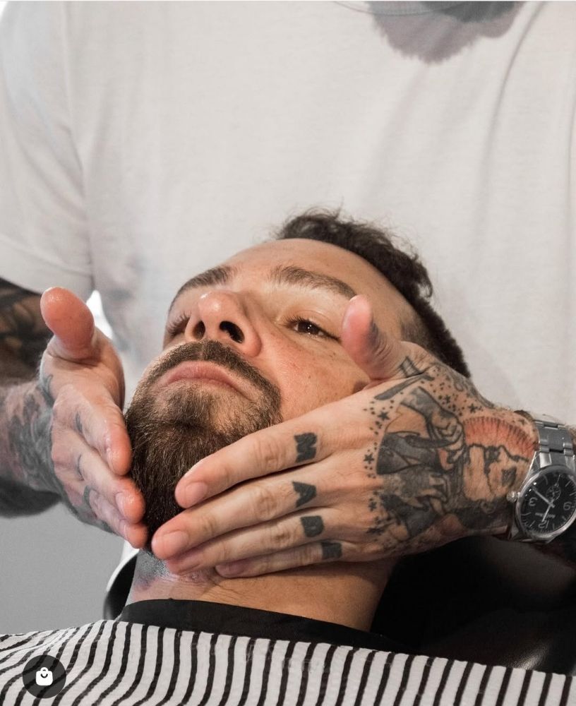 A man is getting his beard shaved by a barber.