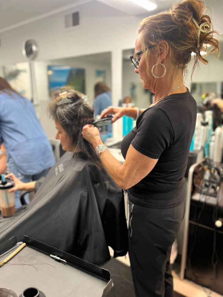 A woman is getting her hair cut by a hairdresser in a salon.