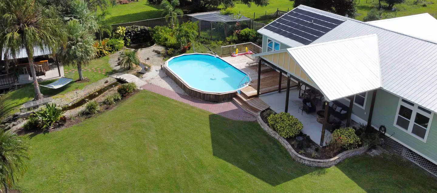 An aerial view of a house with a pool and solar panels on the roof.