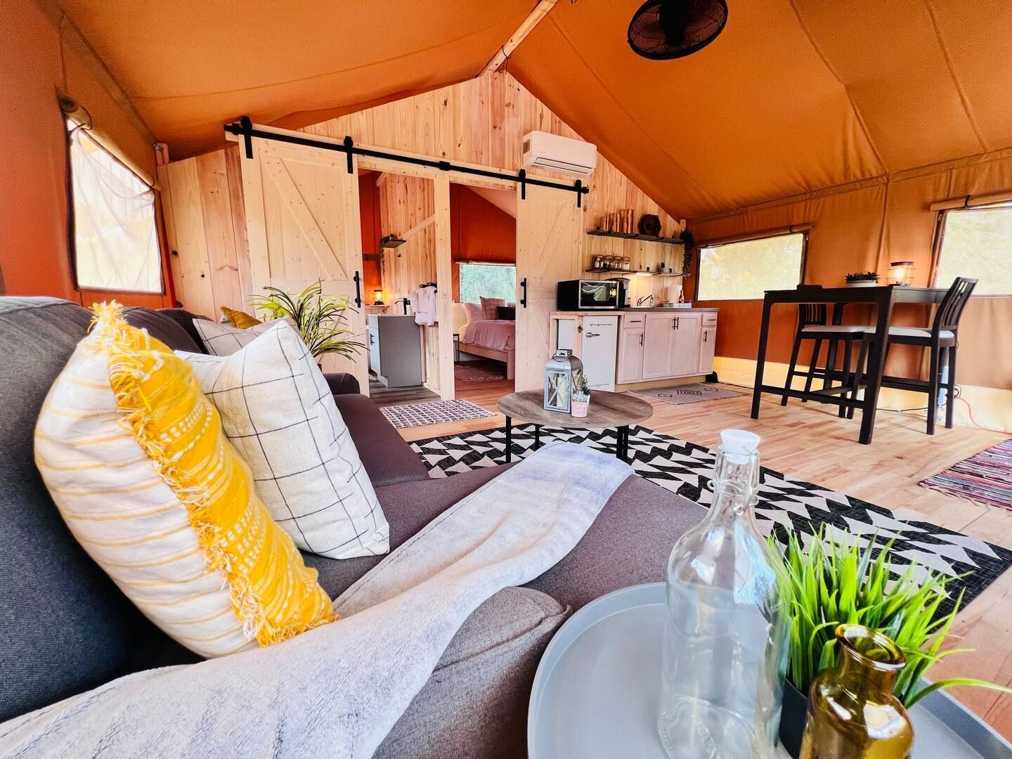 A living room in a tent with a couch , chair and table.