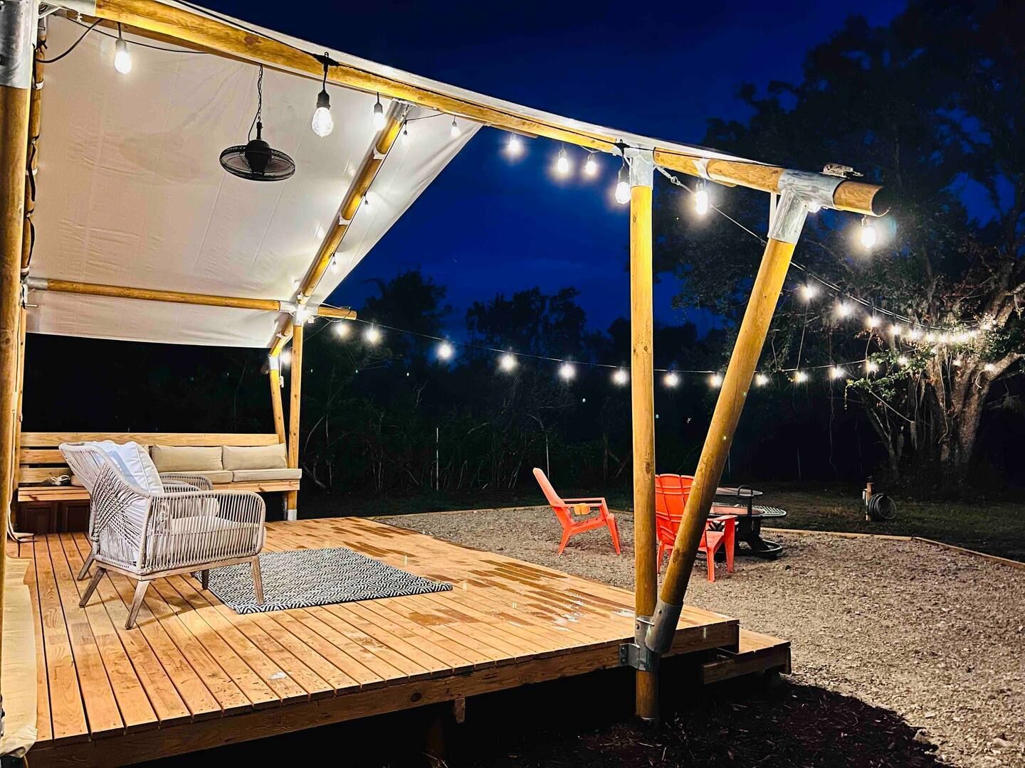 A wooden deck with a canopy and lights at night.