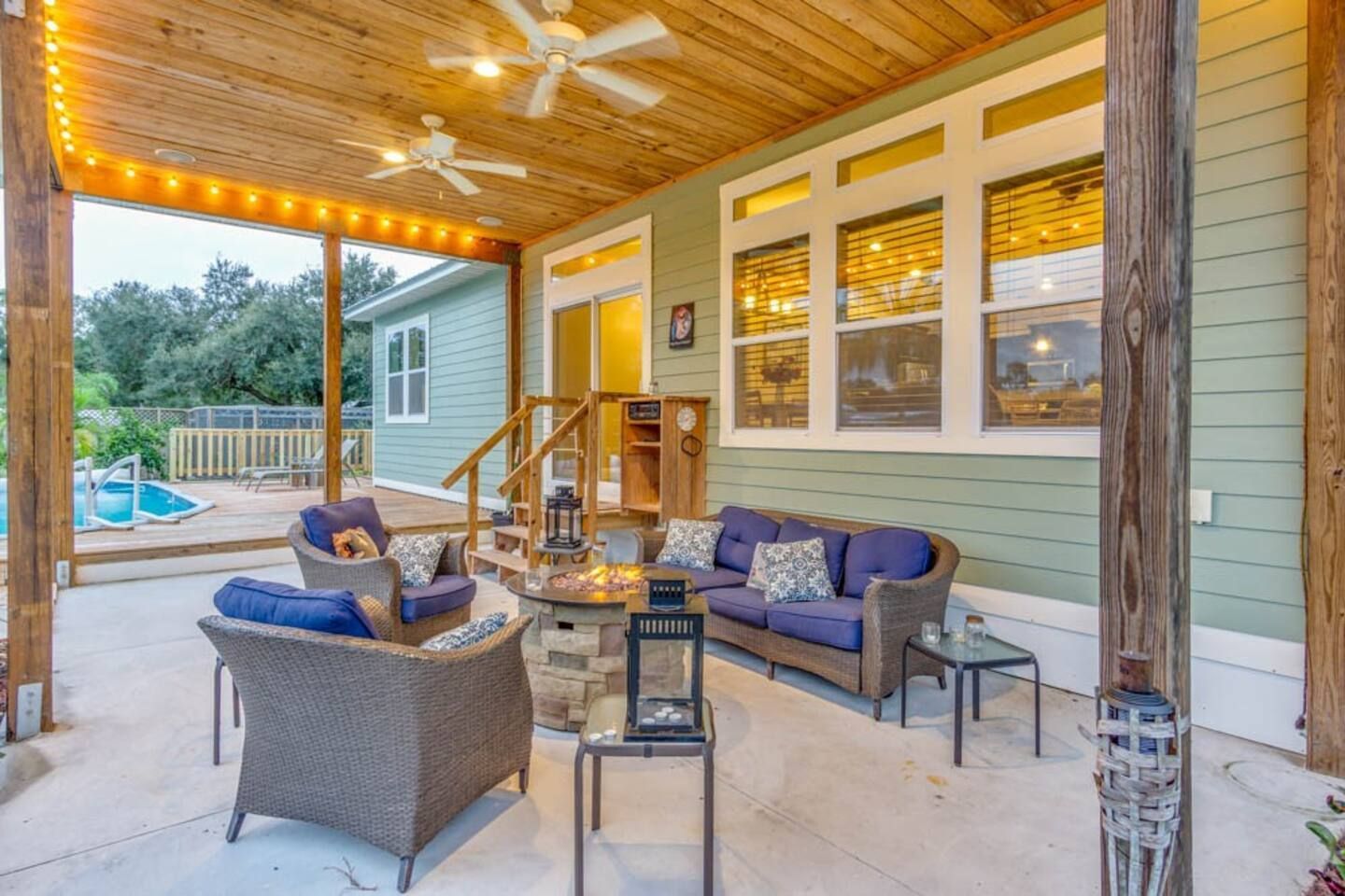 A patio with a couch , chairs , tables and a ceiling fan.