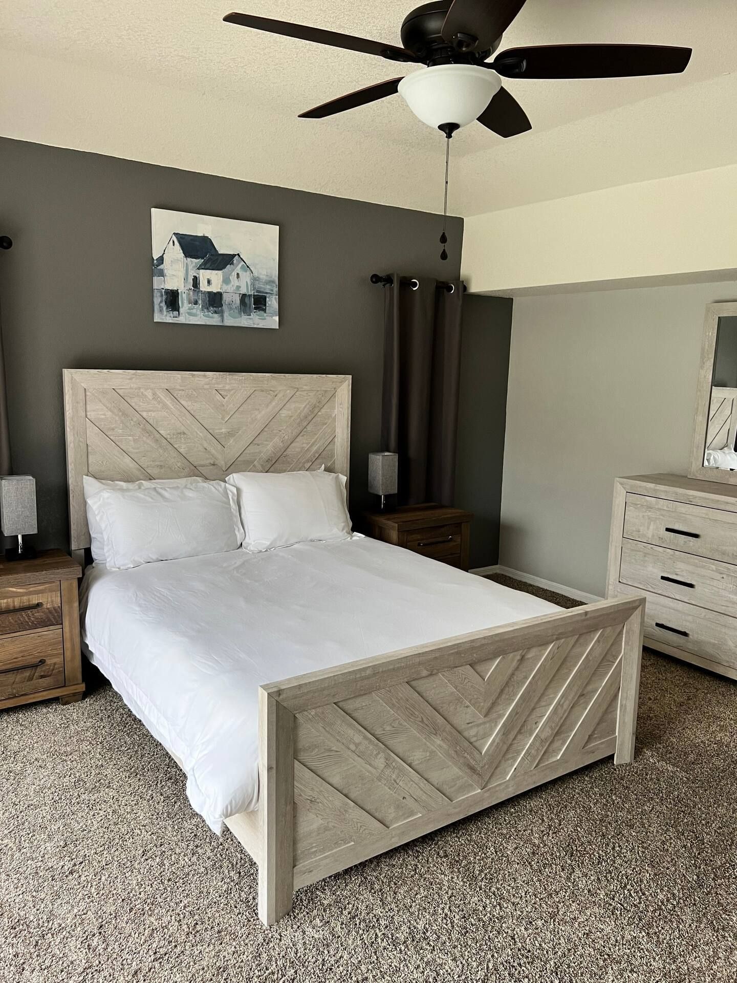 A bedroom with a bed , dresser , nightstand and ceiling fan.