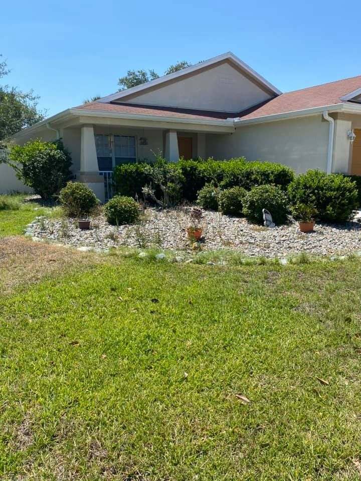 A house with a lush green lawn and bushes in front of it.