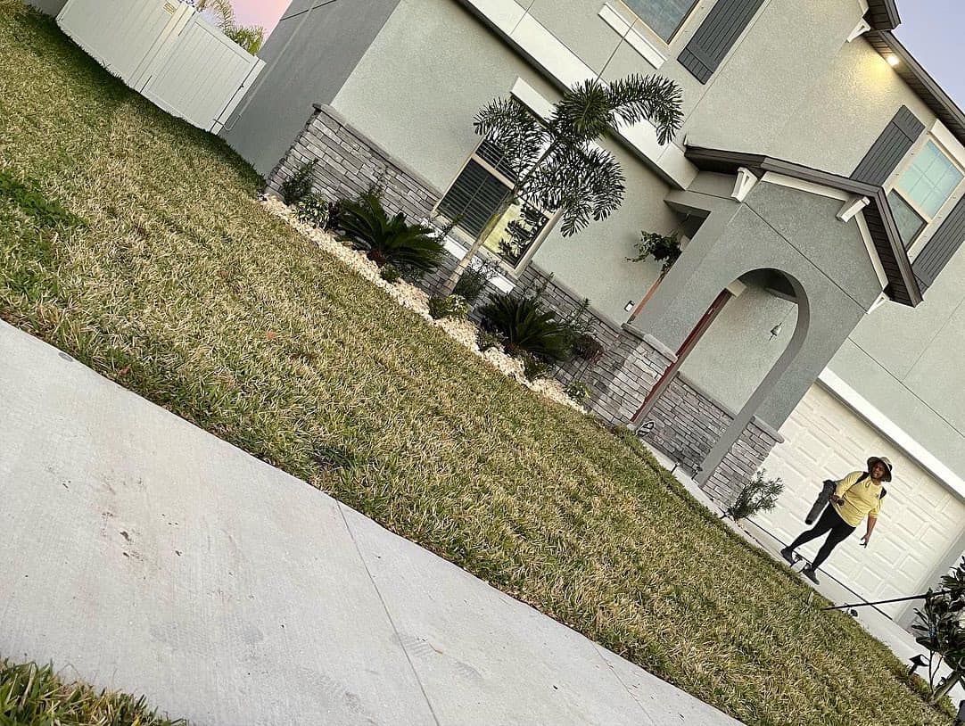 A person is walking a dog on a leash in front of a house.
