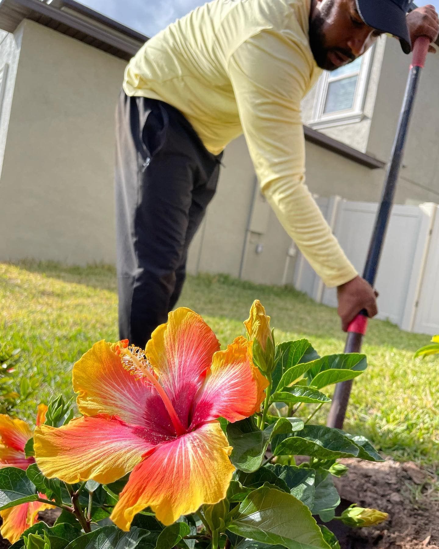 A man is planting flowers in a garden with a shovel.