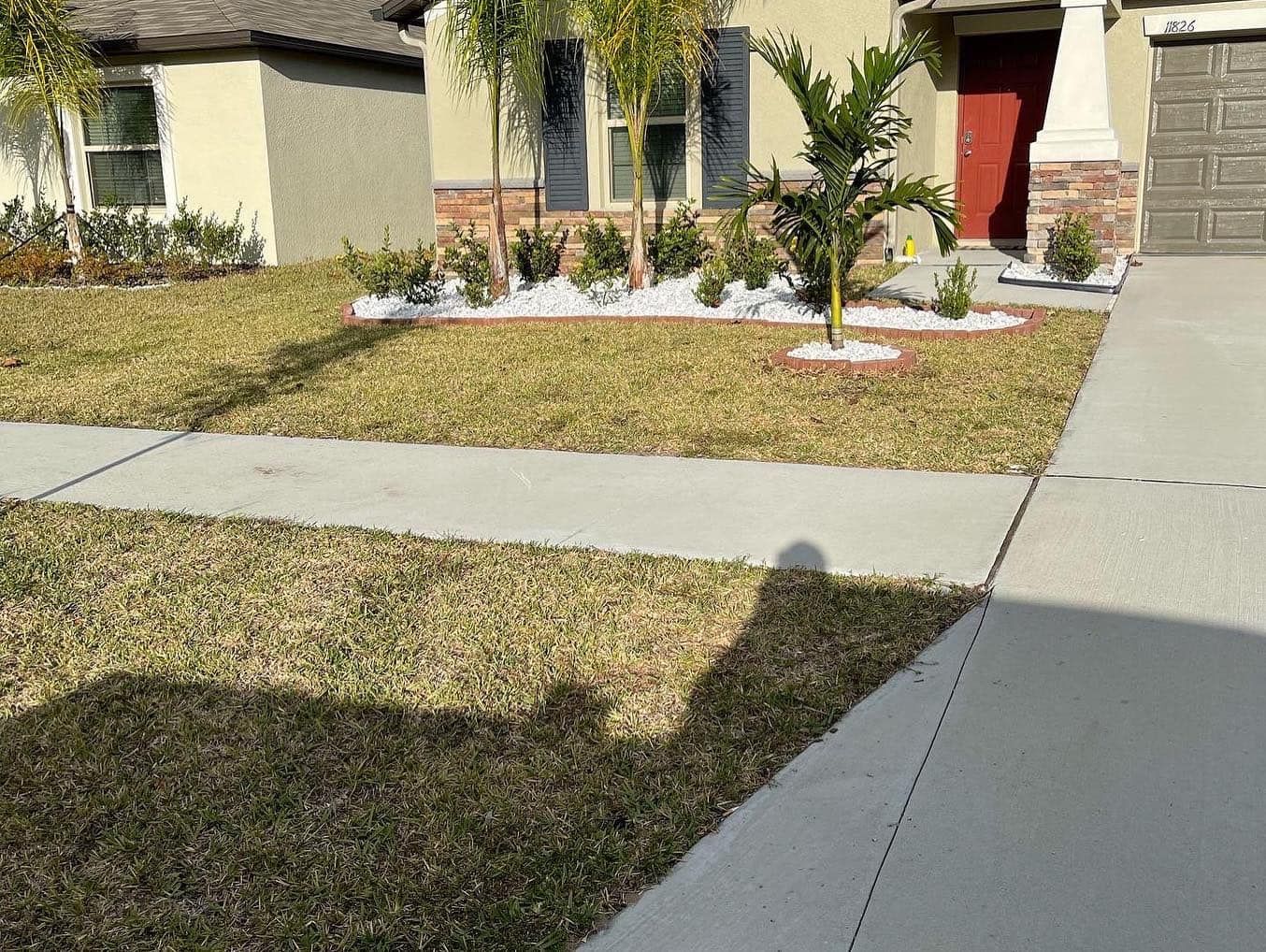 A house with a lush green lawn and a driveway in front of it.