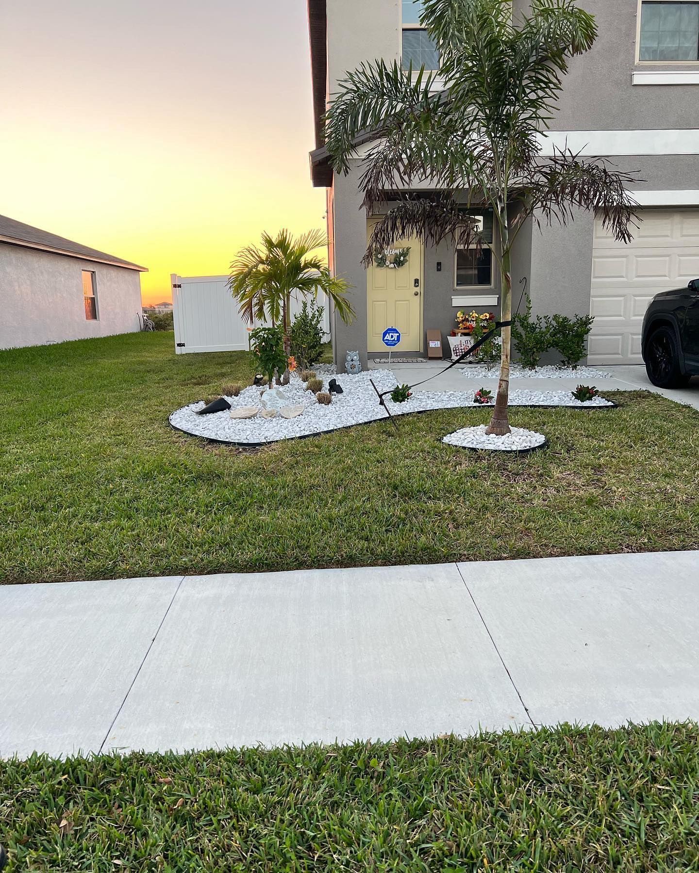 A house with a lush green lawn and a tree in front of it.