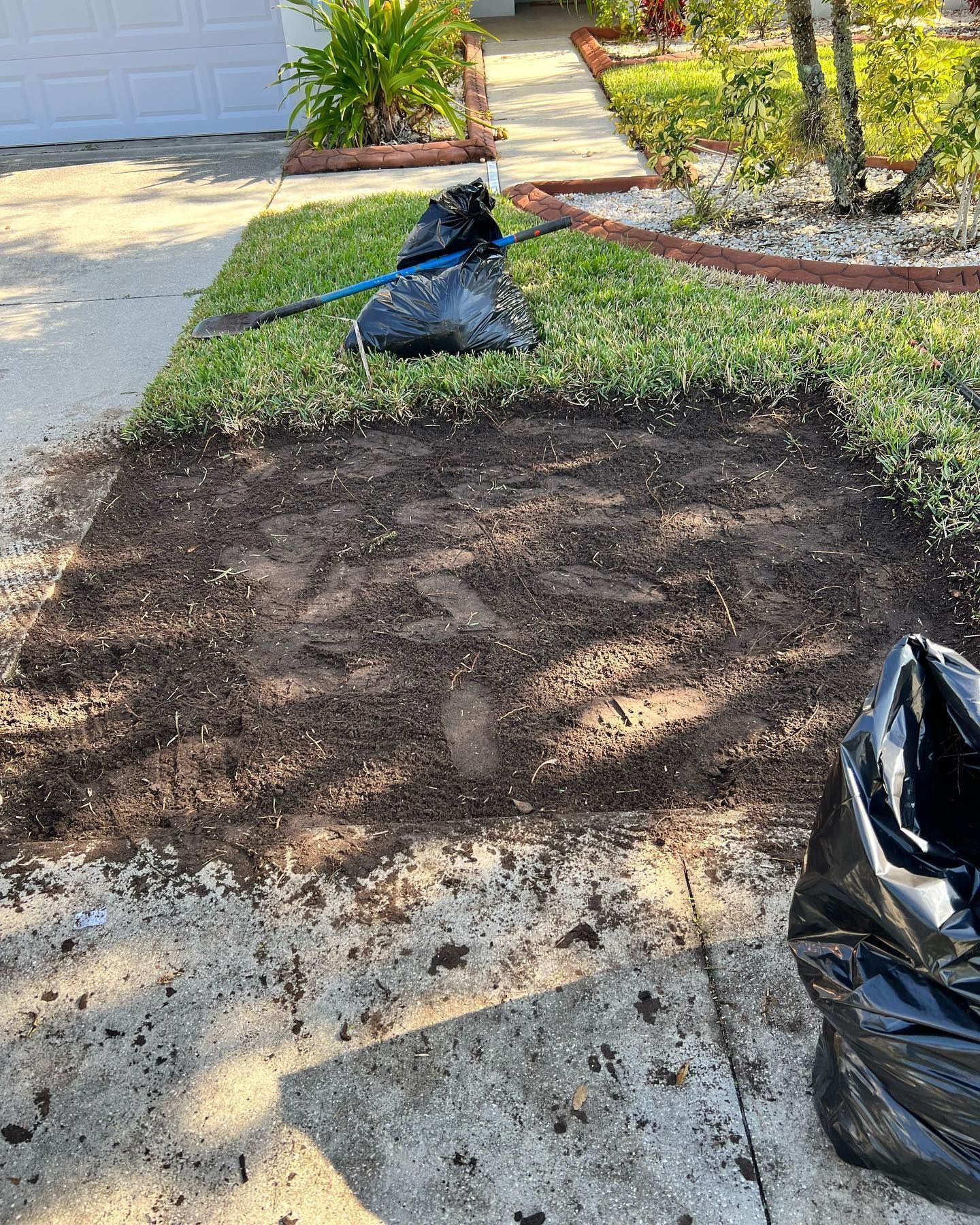 A pile of dirt is sitting on the sidewalk in front of a house.