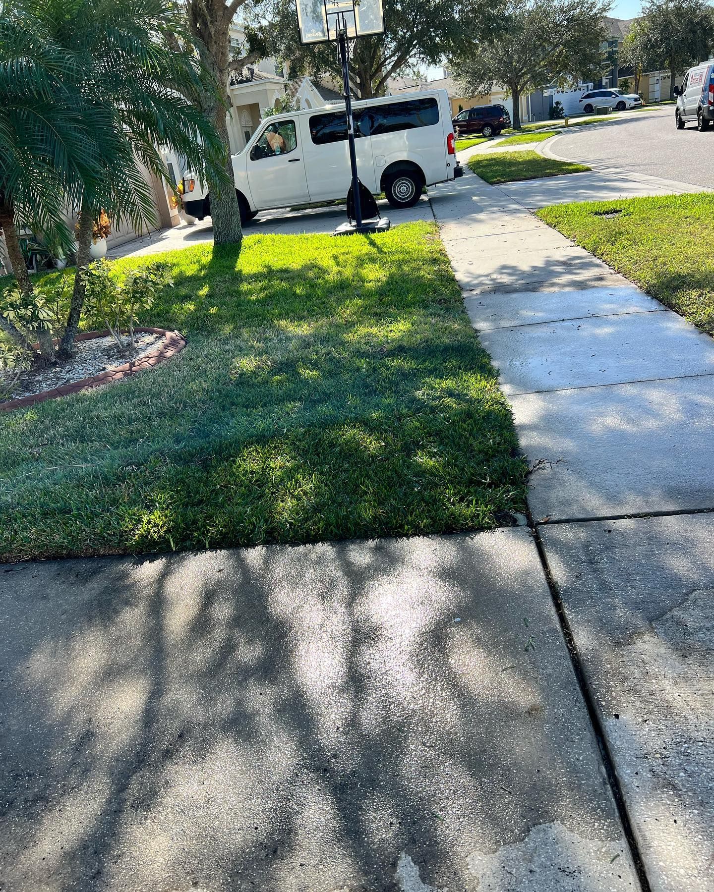 A white van is parked on the side of the road next to a sidewalk.