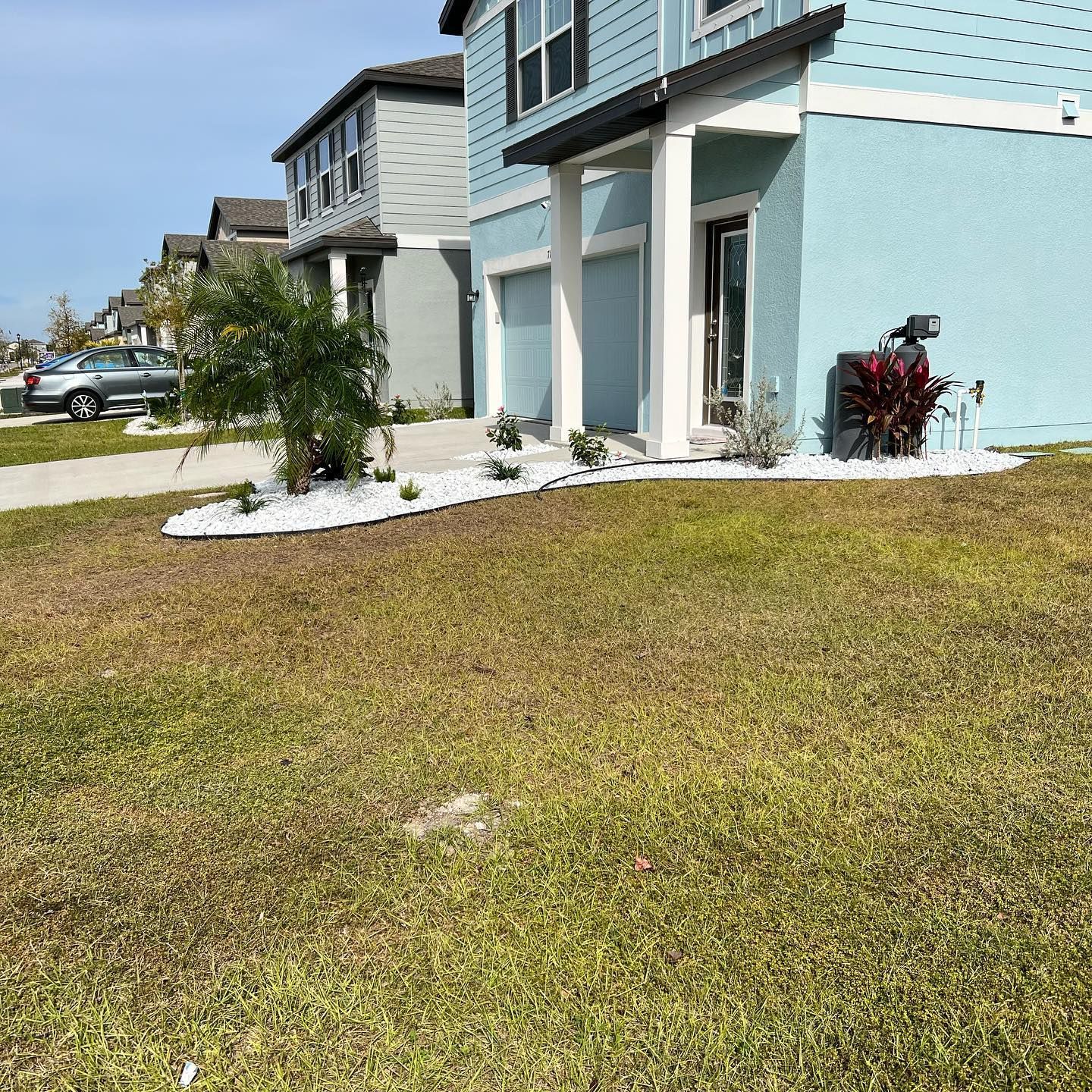A blue house with a lush green lawn in front of it.