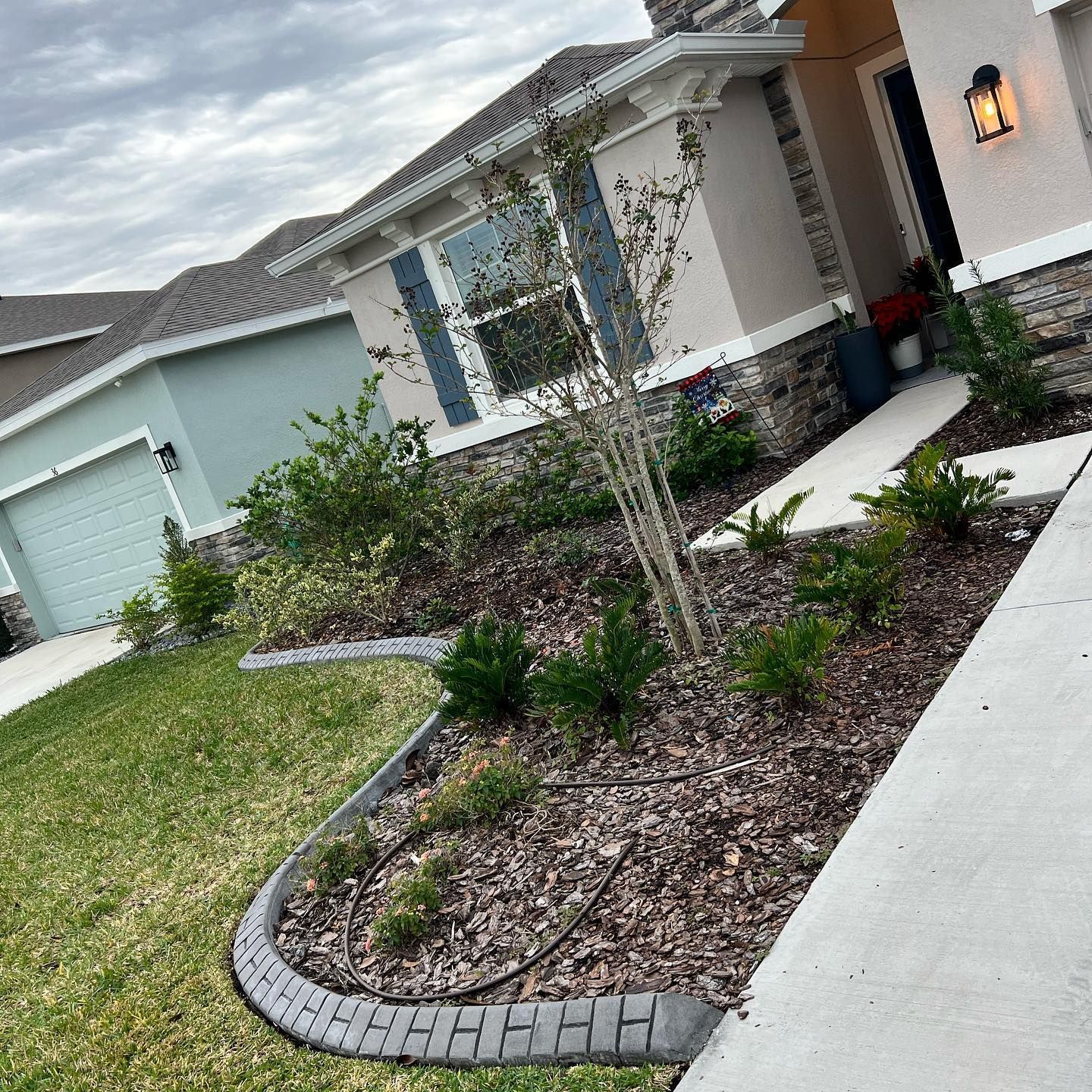 A house with a lush green lawn and a sidewalk in front of it.