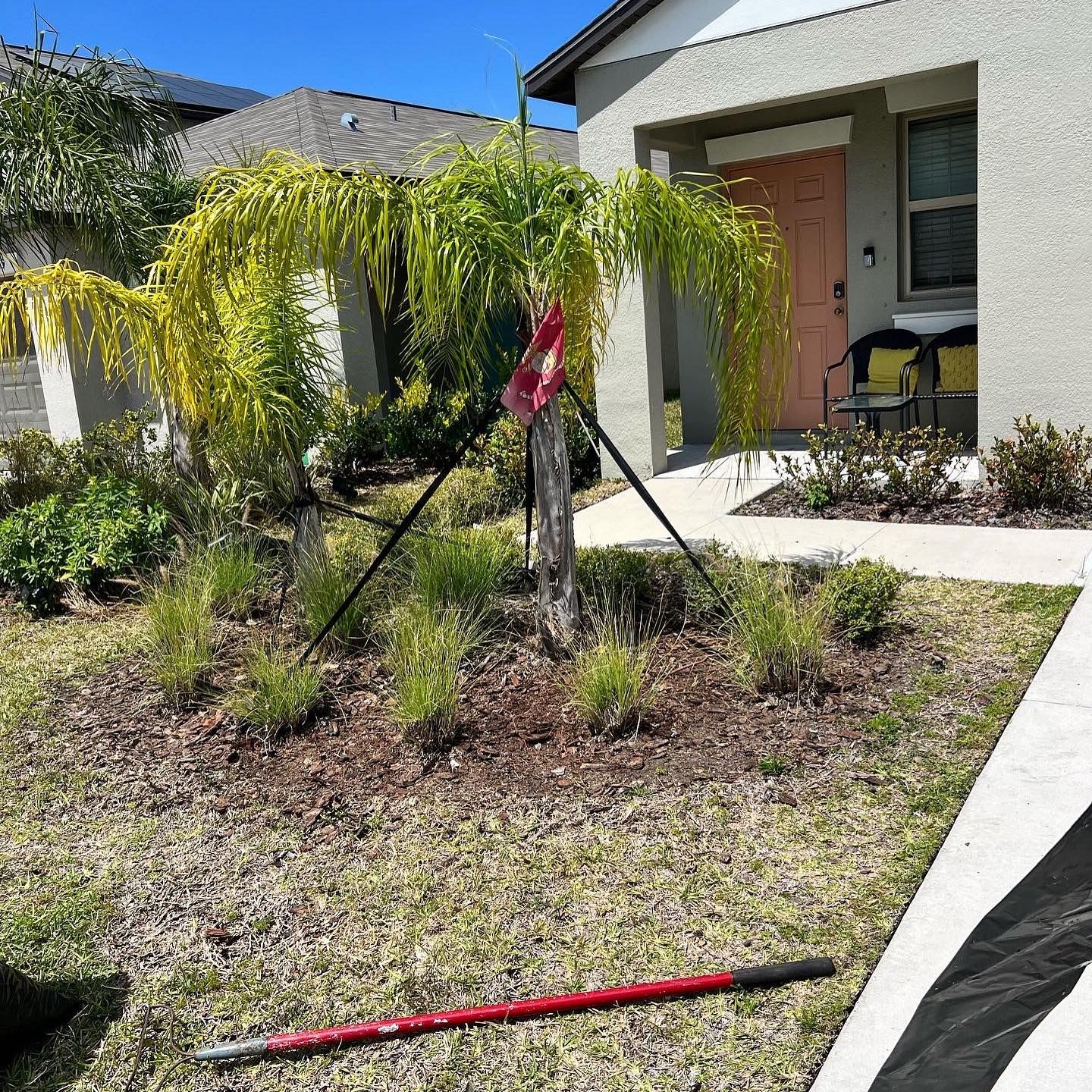 A lawn mower is sitting in the grass in front of a house.
