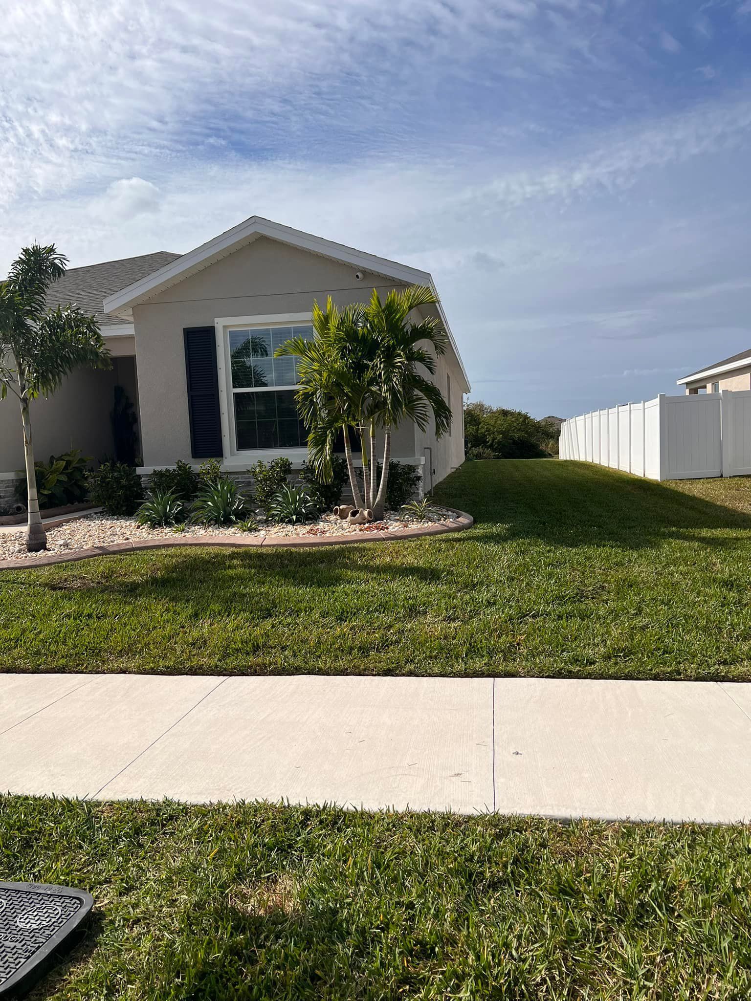 A house with a lush green lawn and a sidewalk in front of it.