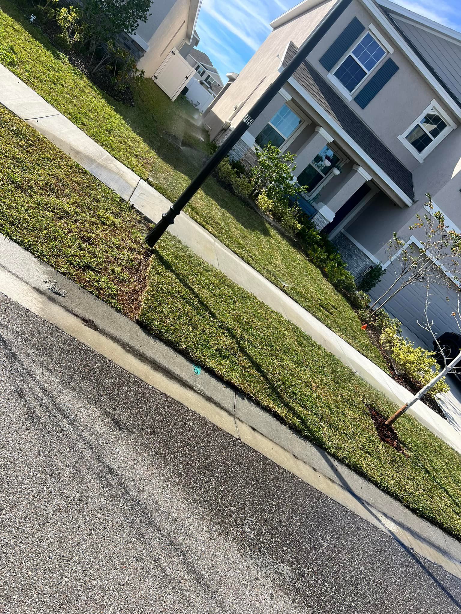 A house is sitting on the side of a road next to a sidewalk.