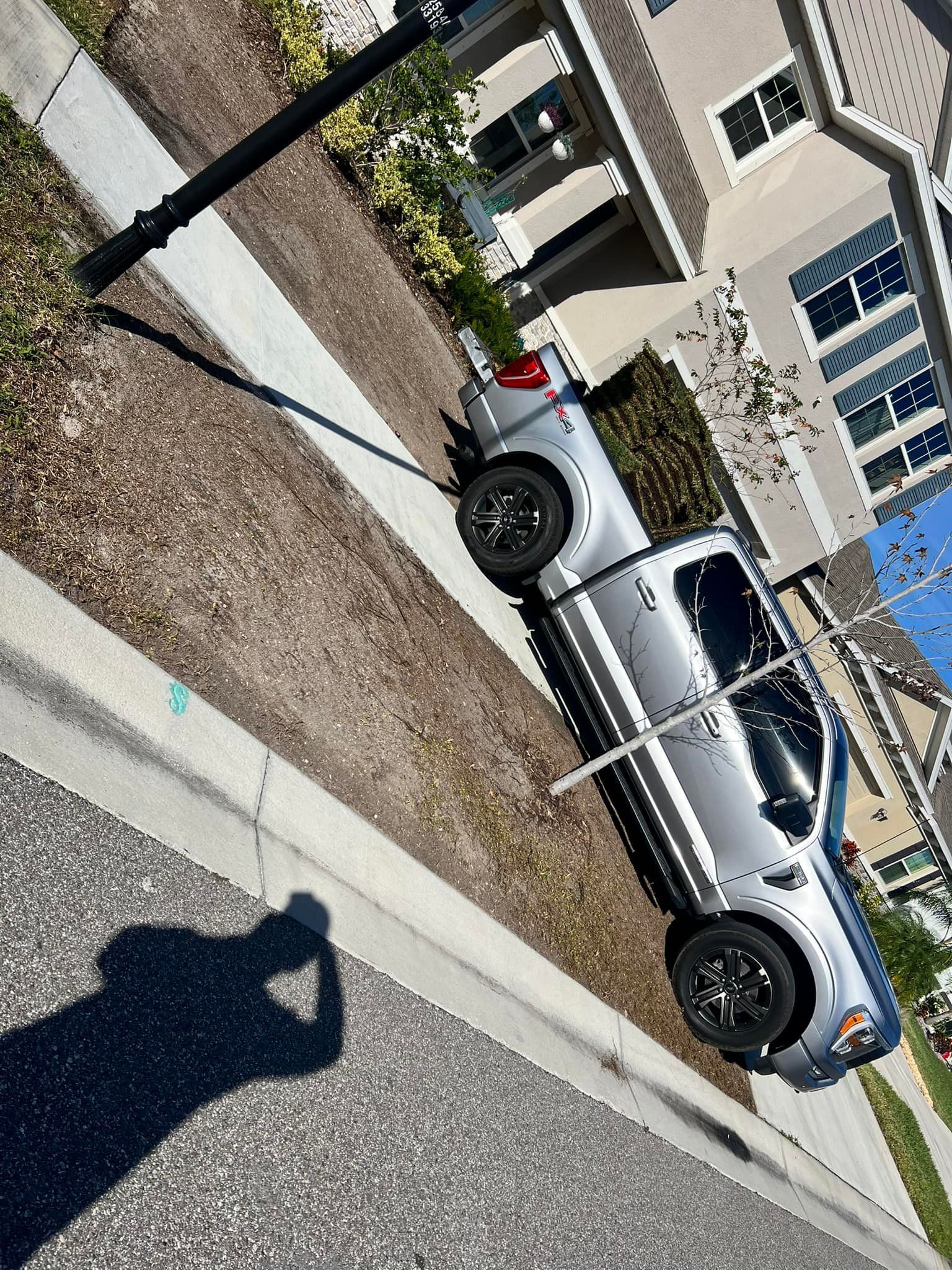 A silver truck is parked on the side of the road next to a house.