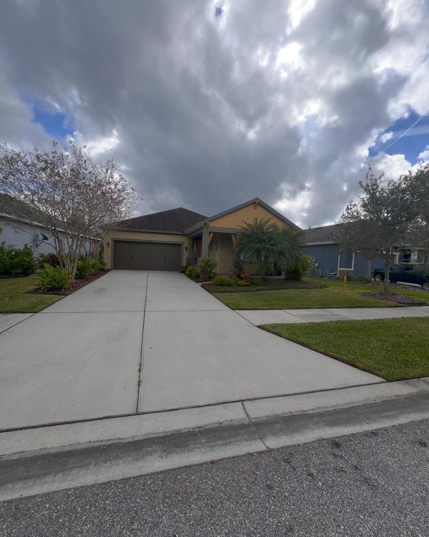 A house with a concrete driveway and a cloudy sky in the background
