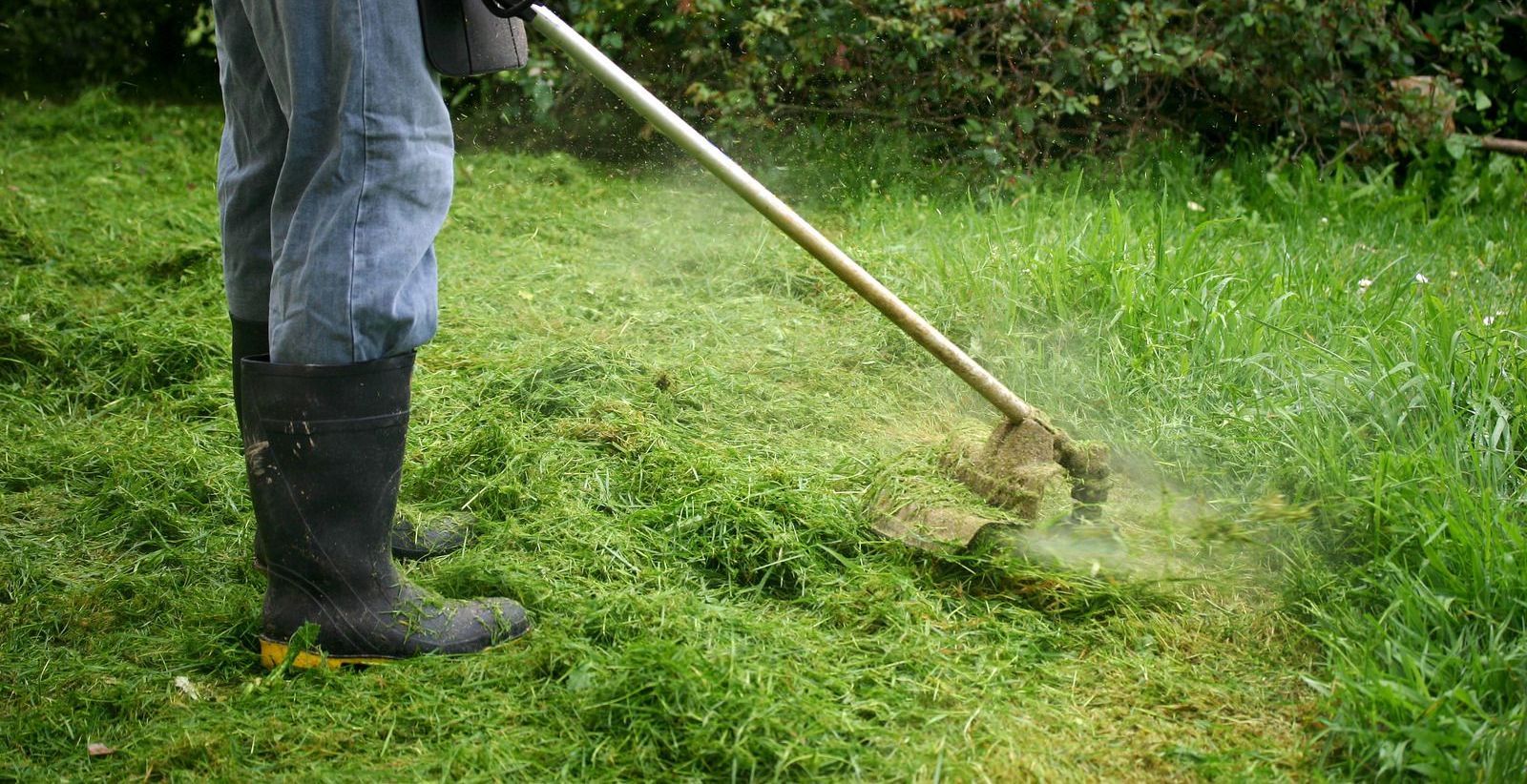 A man is mowing the grass with a lawn mower.