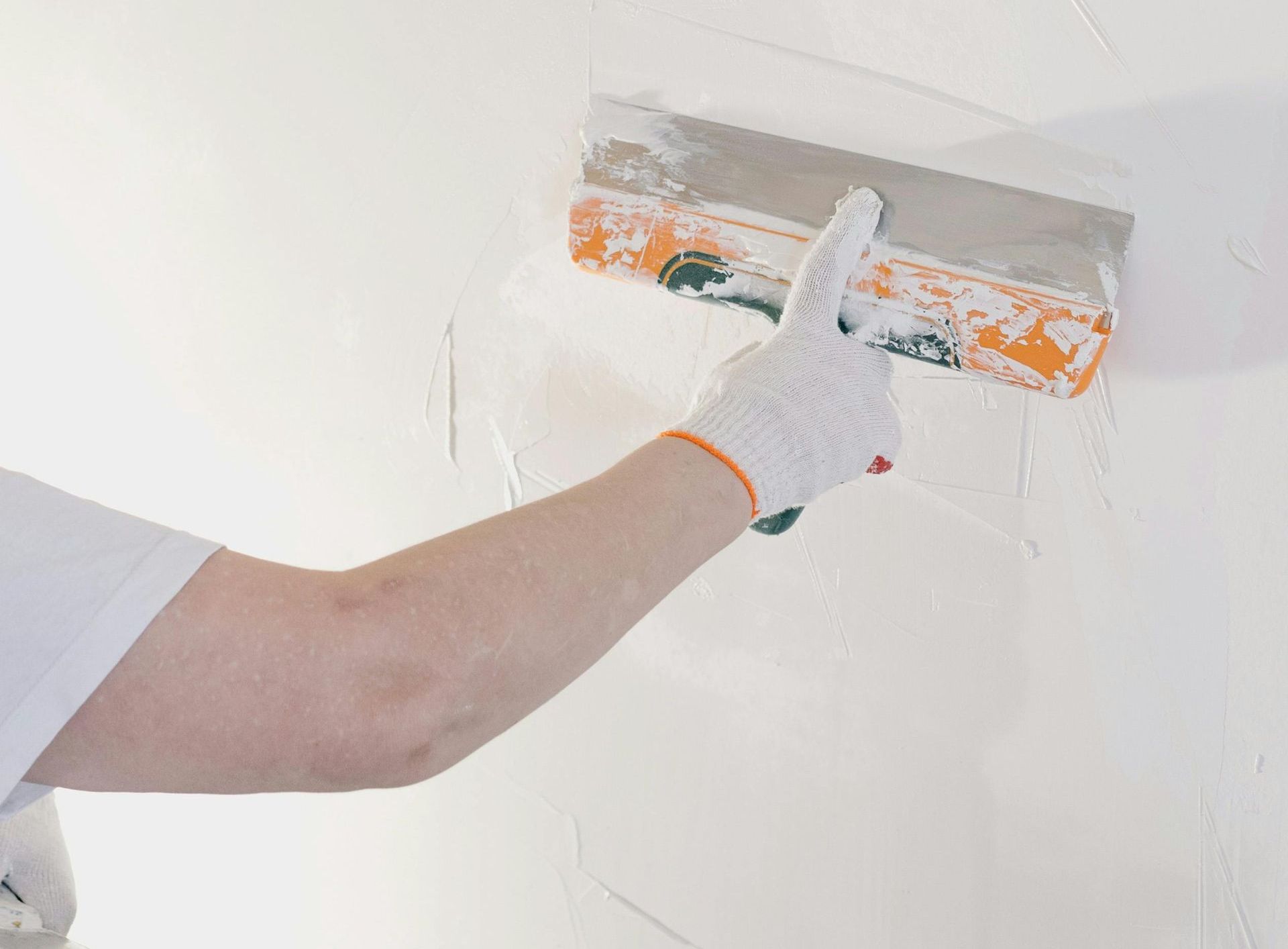 A person is plastering a wall with a trowel.