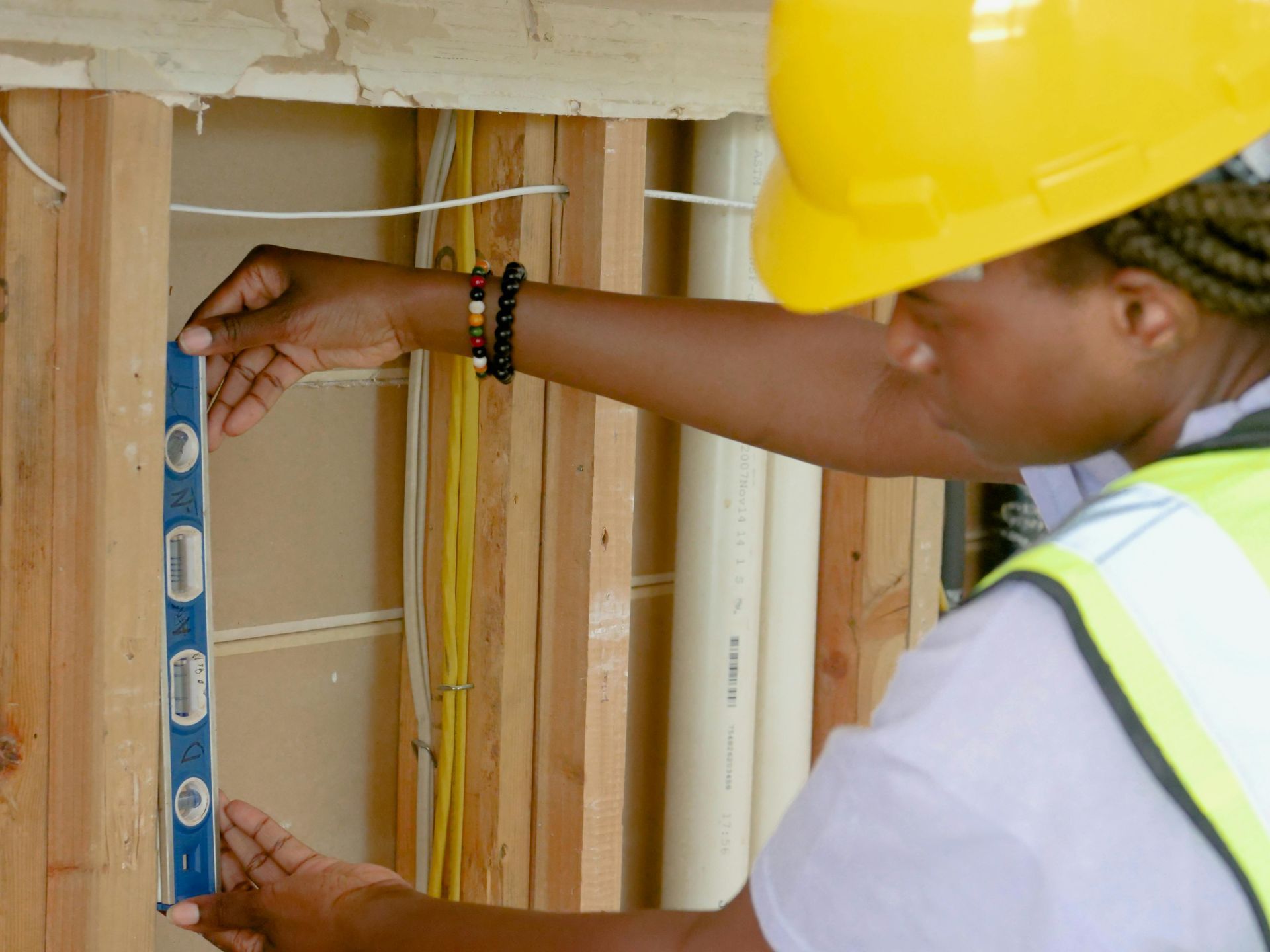 A construction worker is measuring a wall with a level before drywall is installed.