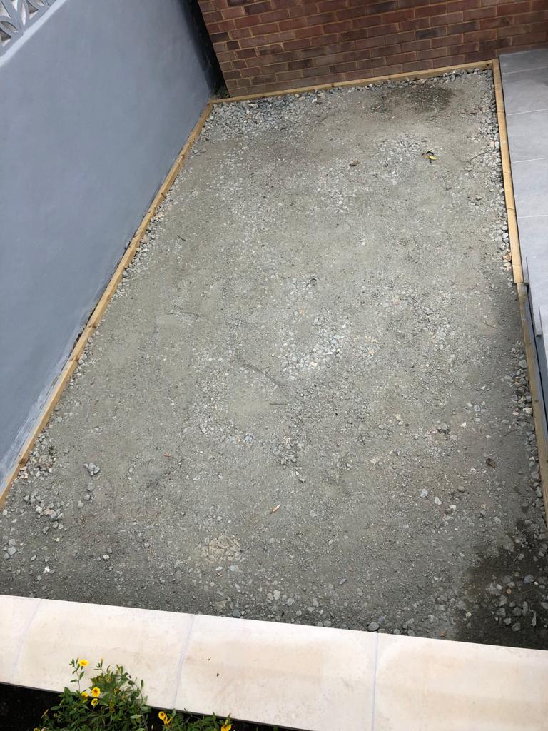 A large pile of gravel is sitting next to a brick wall.