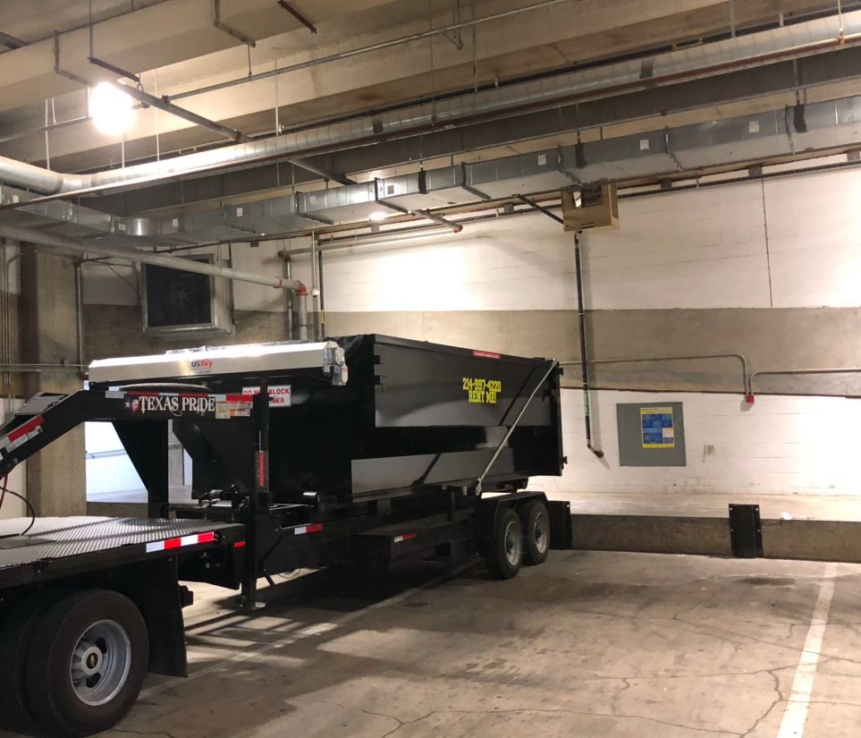 Image shows our Iron Man roll-off container expertly positioned in a parking garage - because yes, we can do that!