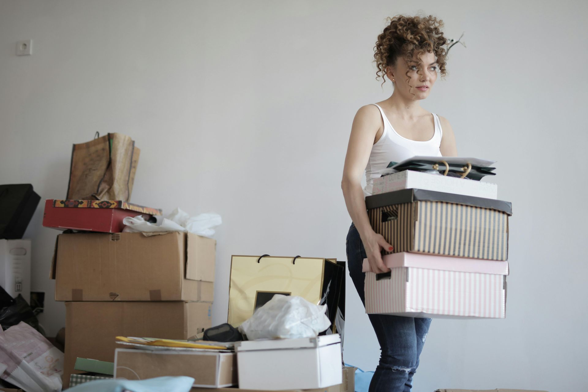 A woman is carrying a pile of boxes in a room.
