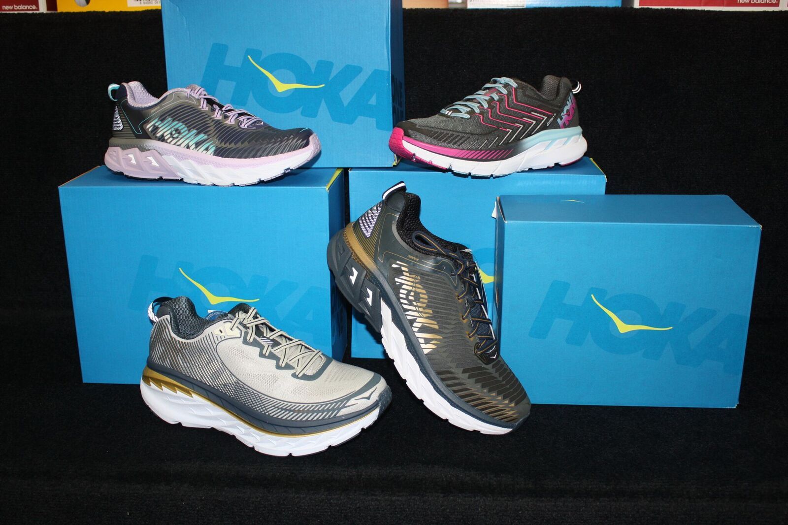 Three pairs of hoka shoes are sitting on top of blue boxes