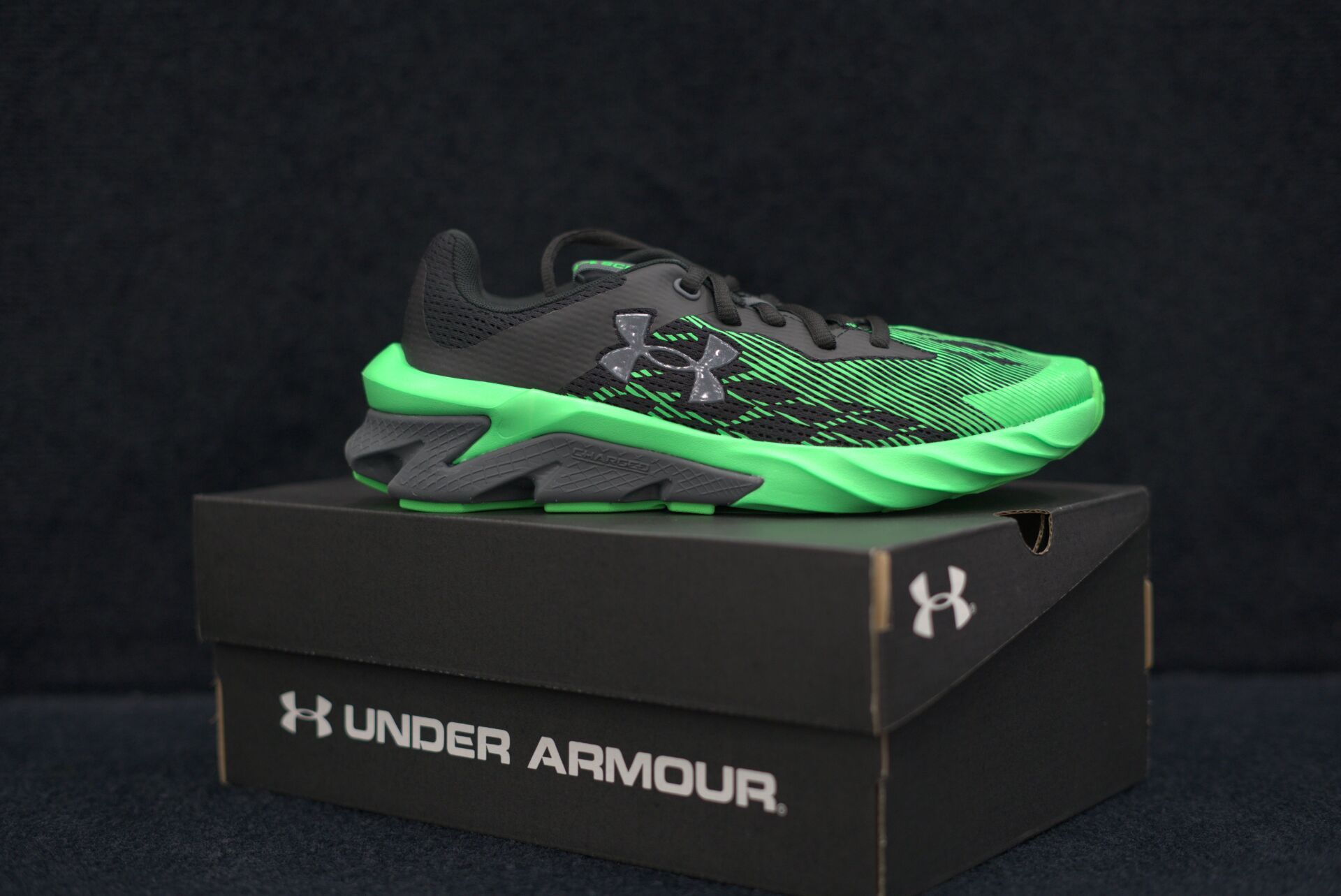 A pair of under armour shoes sitting on top of a black box