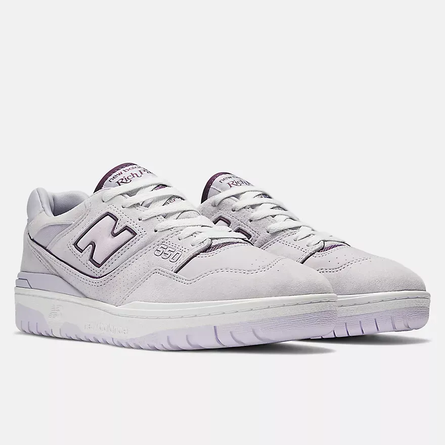 A pair of purple and white new balance 550 sneakers on a white background.