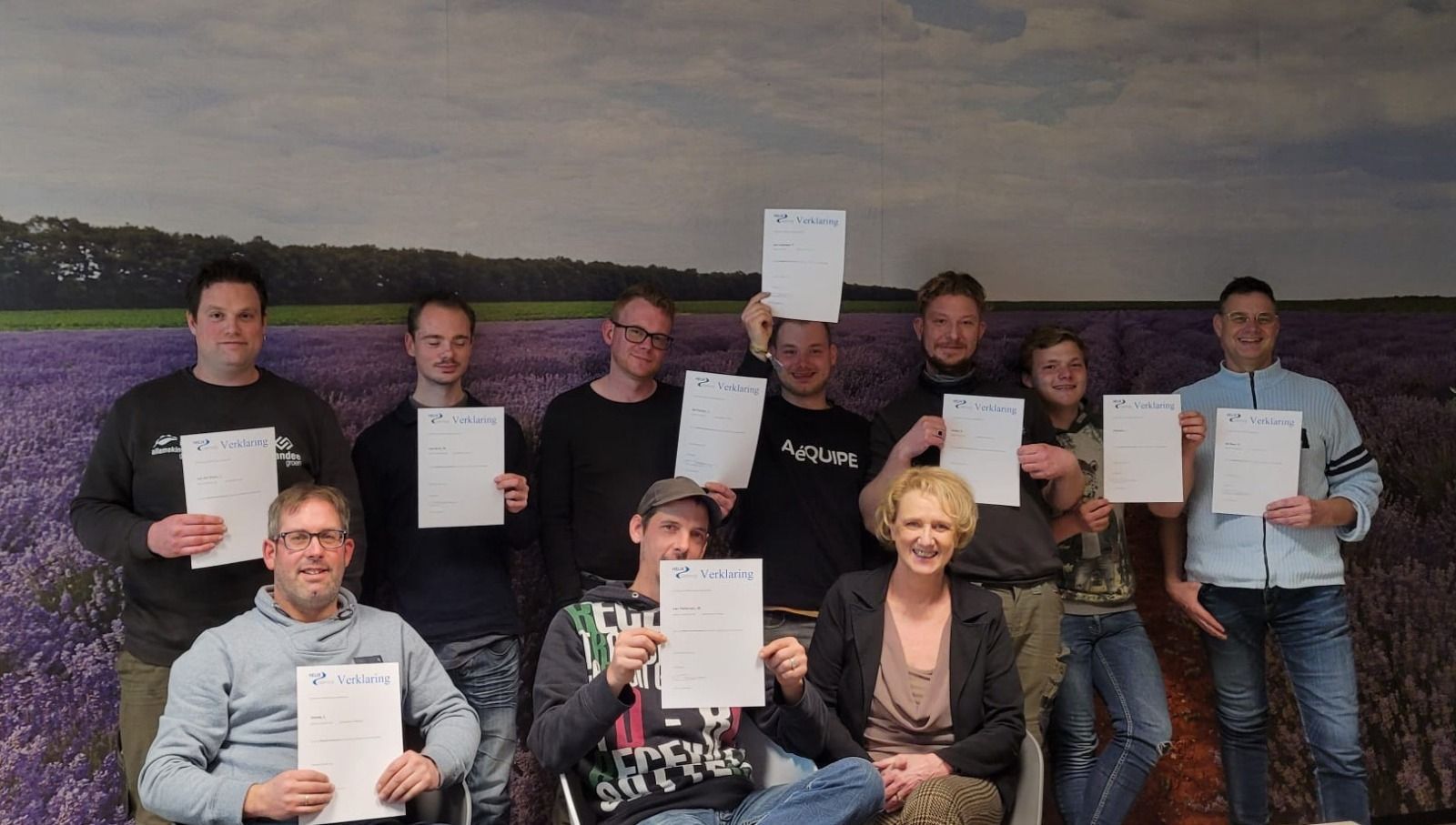 Een groep mensen met een certificaat staat lachend voor een foto landschapsdecor.
