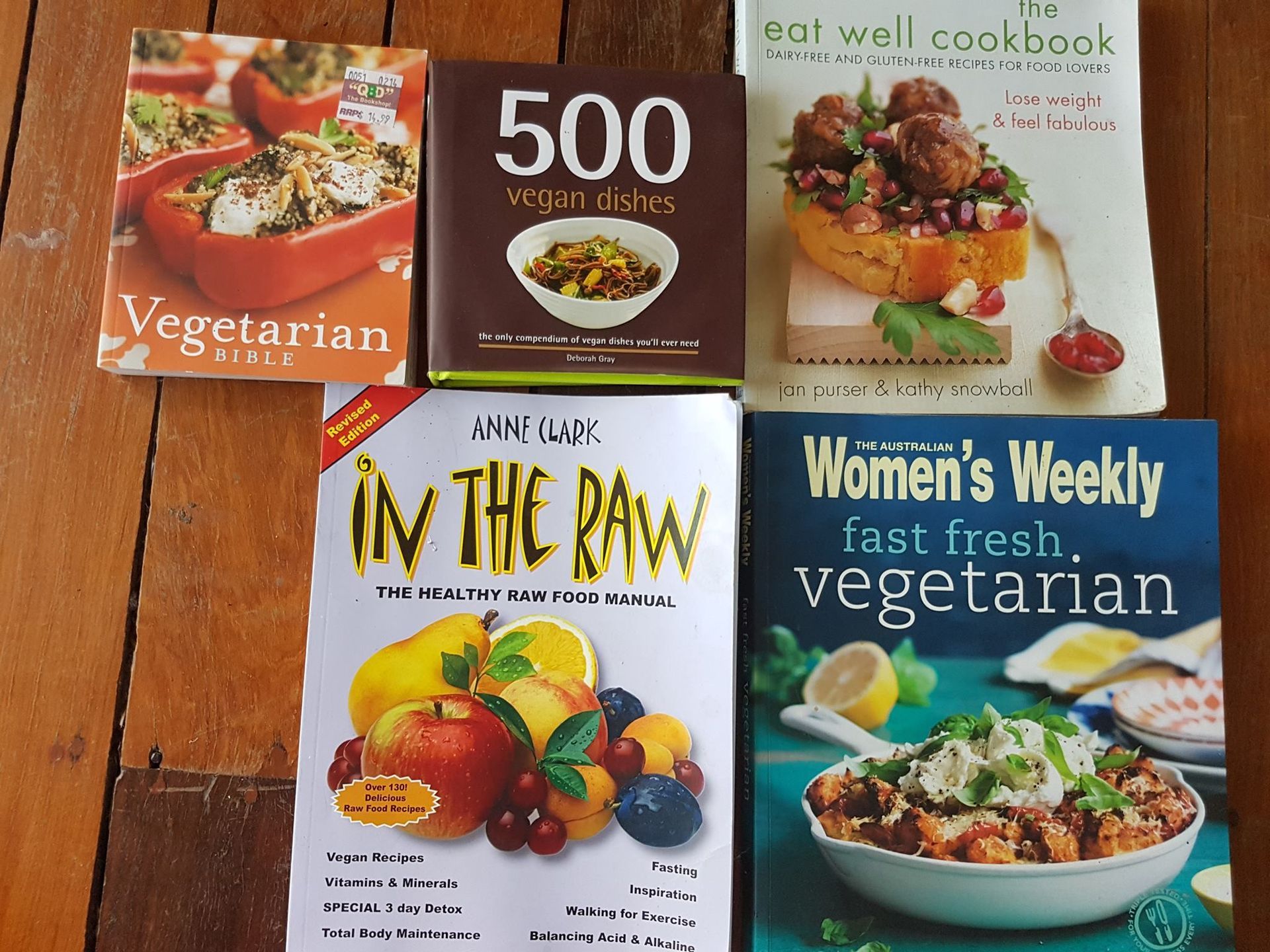 Six vegetarian cookbooks on a wooden surface.