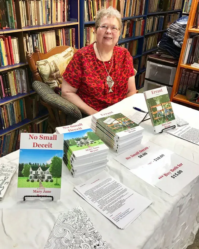Woman at a book table with stacks of books titled